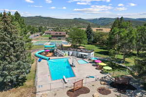 Community pool with a patio area, a water slide, and a mountain view