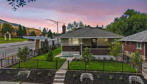 Bungalow featuring brick siding, a fenced front yard, a chimney, a gate, and a shingled roof