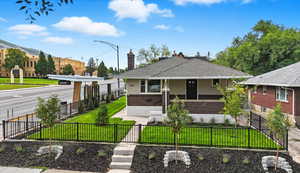View of front of home featuring brick siding, a fenced front yard, a gate, a chimney, and a shingled roof