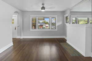 Unfurnished dining area with arched walkways, dark wood-type flooring, and ceiling fan