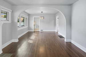 Unfurnished dining area with arched walkways and dark wood-style flooring