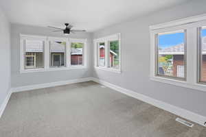 Empty room with light carpet, plenty of natural light, and a ceiling fan