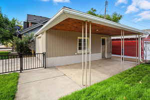 View of the covered patio with a gate and an outdoor hangout area between the home and garage
