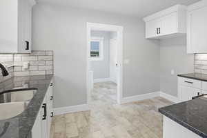 Kitchen featuring backsplash, white cabinets, and dark stone counters