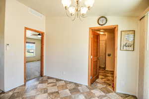 Unfurnished dining area with stone finish floors, a chandelier, and a ceiling fan