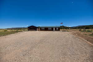 Single story home featuring a mountain view, driveway, a garage, and an outbuilding