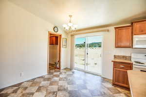 Unfurnished dining area featuring stone finish floors and a chandelier