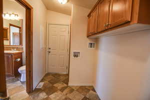Laundry area featuring washer hookup, stone finish flooring, and cabinet space