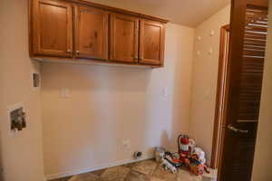Washroom with washer hookup, cabinet space, and a textured ceiling