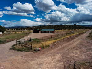 View of dirt / gravel road with a view of countryside, a mountain view, and a pole building