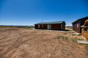 Back of property featuring a mountain view, a metal roof, and a rural view
