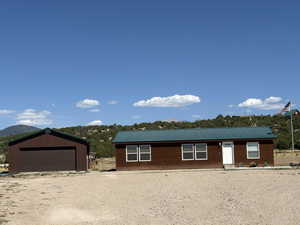 View of front facade with a metal roof, a detached garage, an outdoor structure, and a mountain view