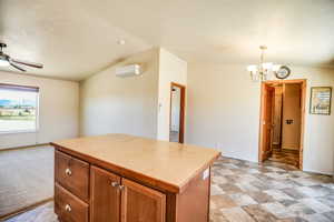 Kitchen with light countertops, brown cabinets, a center island, a chandelier, and vaulted ceiling