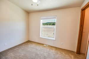 Carpeted empty room with ceiling fan