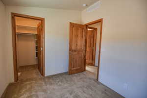 Unfurnished bedroom with carpet and a walk in closet