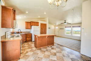 Kitchen with lofted ceiling, a kitchen breakfast bar, white appliances, light countertops, and brown cabinetry