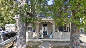 View of front of home with a porch, stucco siding, and roof with shingles