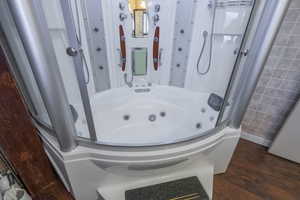 Bathroom featuring a stall shower, dark wood finished floors, and a tub with jets