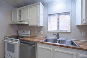 Kitchen with white range with electric stovetop, dishwasher, white cabinets, and wood counters