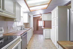 Kitchen featuring appliances with stainless steel finishes, lofted ceiling, ceiling fan, healthy amount of natural light, and ventilation hood