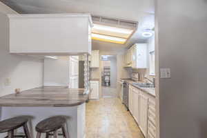 Kitchen featuring lofted ceiling, a kitchen bar, electric range, white cabinets, and a peninsula
