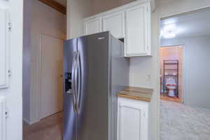 Kitchen featuring white cabinetry, wood counters, and stainless steel refrigerator with ice dispenser