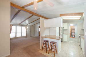Kitchen with white cabinetry, a breakfast bar, open floor plan, butcher block countertops, and appliances with stainless steel finishes