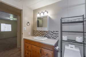 Half bathroom with vanity and backsplash
