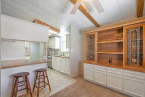 Kitchen featuring a kitchen breakfast bar, light carpet, white cabinets, glass insert cabinets, and open shelves