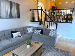 Living room with light wood-style floors, a chandelier, recessed lighting, and stairway