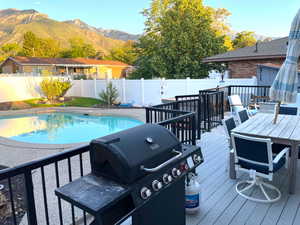 View of pool with area for grilling, a deck with mountain view, a fenced backyard, and outdoor dining space