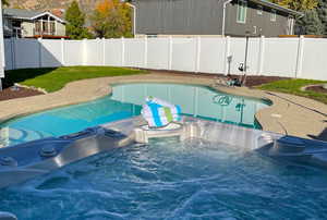 View of swimming pool featuring a hot tub, a fenced backyard, and a patio