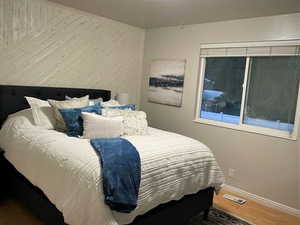 Bedroom with wood finished floors and wooden walls