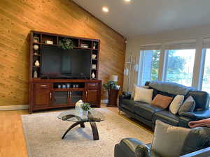 Living room featuring wood walls, light wood-style flooring, and recessed lighting
