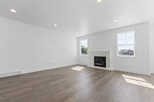 Unfurnished living room featuring recessed lighting, a glass covered fireplace, and hardwood / wood-style floors