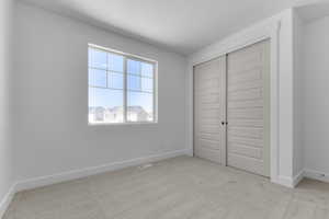 Unfurnished bedroom featuring light colored carpet and a closet