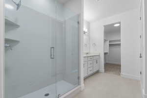 Bathroom with vanity, a shower stall, light tile patterned floors, and a spacious closet