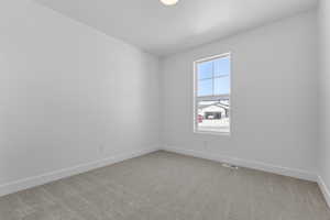 Carpeted spare room featuring baseboards