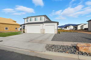 View of front facade featuring a mountain view, concrete driveway, a garage, and stone siding