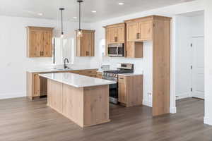Kitchen featuring appliances with stainless steel finishes, decorative light fixtures, recessed lighting, dark wood finished floors, and a center island