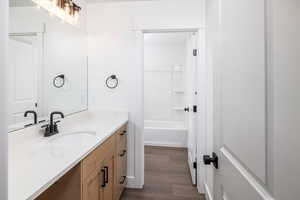 Bathroom featuring vanity, dark wood finished floors, and washtub / shower combination