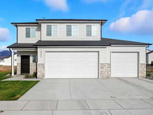 View of front of home with stone siding, driveway, roof with shingles, a front lawn, and a mountain view