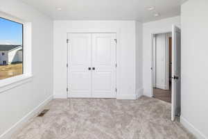 Unfurnished bedroom with light colored carpet, a closet, and recessed lighting