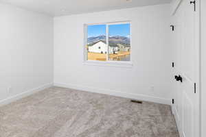 Unfurnished room with light colored carpet and a mountain view