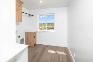 Washroom with dark wood-style floors, cabinet space, hookup for a washing machine, hookup for an electric dryer, and recessed lighting