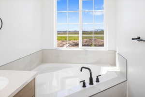 Bathroom with a bath, plenty of natural light, vanity, and a mountain view