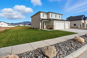 View of front of house with stone siding, a front lawn, driveway, a mountain view, and a residential view