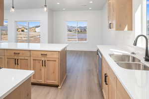 Kitchen featuring light brown cabinets, decorative light fixtures, light wood finished floors, light stone counters, and recessed lighting