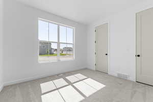 Unfurnished bedroom featuring light carpet and a residential view