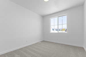 Empty room with light colored carpet and baseboards